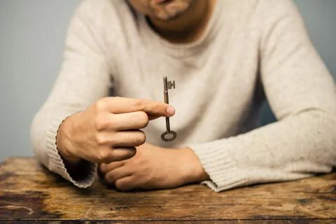 Man at table holding a key Stock-Fotos