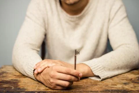 Man at table holding a key Stock Photos