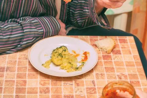 Man at the table in the kitchen eating potatoes Stock Photos