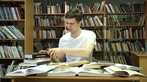 Man at the table in the library with a lot of books 스톡 동영상 155962906