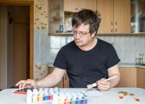 Man at the table with a tablet and paints in the foreground Foto stock
