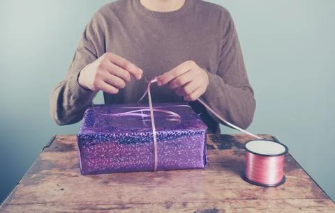Man at table wrapping presents Foto stock
