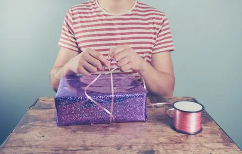 Man at table wrapping presents 스톡 사진
