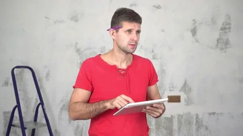 A man with a tablet computer on the background of repairs in the house Vidéo 144451520