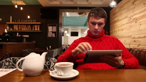 Man with tablet computer drinking tea in cafe Vídeo Stock 71834386