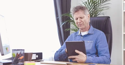Man with tablet computer at his desk in a home office 스톡 동영상 61135609