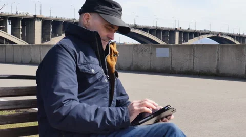 Man with tablet computer sitting on bench in the city Stock Footage 62504023
