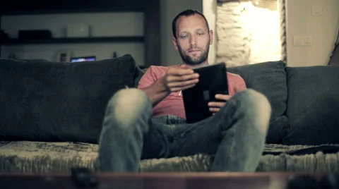 Man with tablet computer sitting on sofa at home HD Stock Footage 33779865