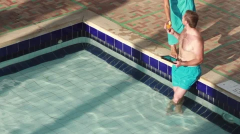 Man with tablet computer by the swimming pool gets drink HD Video stock 10815418