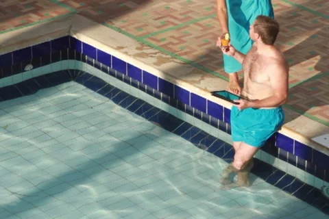 Man with tablet computer by the swimming pool gets drink NTSC Video stock 10815425