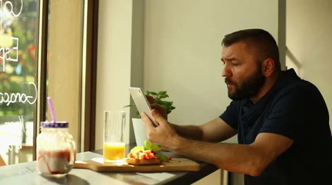 Man with tablet drink orange juice in cafe Stock Footage 67994680