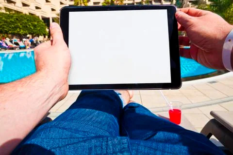 Man with tablet next to a hotel pool. Point of view Stock Photos