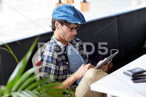 Man with tablet pc and earphones sitting at cafe Stock Photos