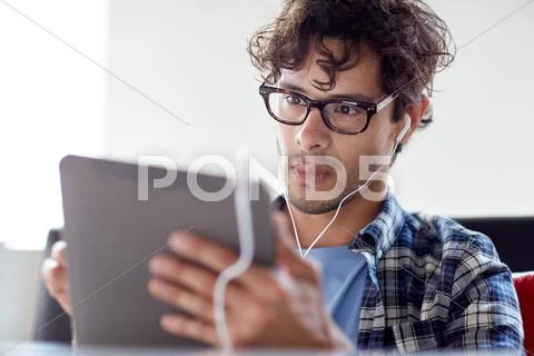 Man with tablet pc and earphones sitting at cafe Stock Photos