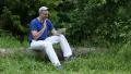 Man with Tablet PC sits on a fallen tree in the forest HD Footage
