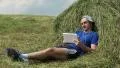 Man with tablet PC sits near haystack HD Footage