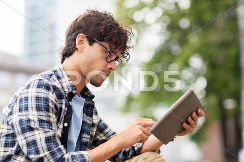 Man with tablet pc sitting on city street bench Stock Photos