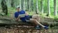 Man with tablet PC sitting on a log in forest HD Footage