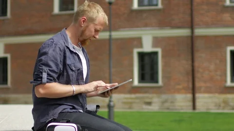 A man with a tablet sits on the street Video stock 91232545