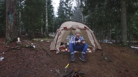 Man with a tablet sits in a tent in the forest 스톡 동영상 90131618