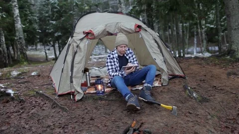 Man with a tablet in a tent on the shore of a winter lake Stock Footage 83146131