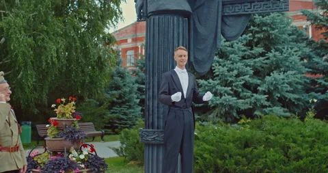 Man in a tailcoat performs in front of women in beautiful dresses and a man in a Stock-Footage 226861475