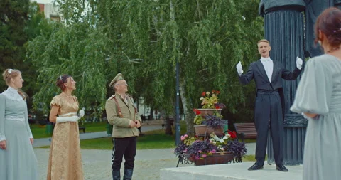 Man in a tailcoat performs in front of women in beautiful dresses and a man in a Stock Footage 227646910