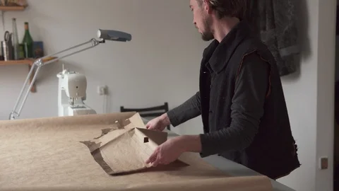 Man tailor creates clothing pattern while working in workshop Stock Footage 100617299