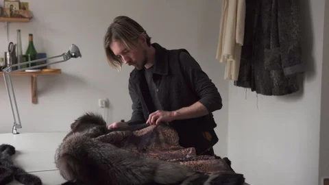 Man tailor touching fur for sewing coat in furrier workshop Stock Footage 100617271