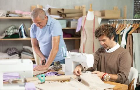 Man tailor at work, other man draw dress pattern on paper Stock Photos