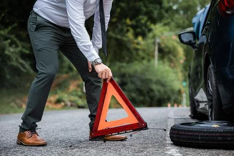 Man take down red warning triangle. Stock Photos