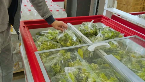 Man take frozen broccoli vegetable in package from refrigerator in store Stock Footage 220483365