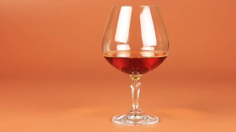 Man take a glass with brandy over brown background Stock Footage 63024752