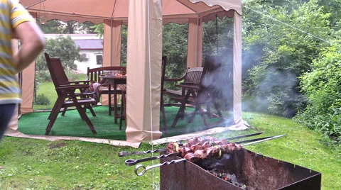 Man take meat and vegetables baked on fire to outdoor bower Stock Footage 50690242