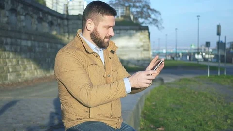 Man take panoramic photo of the river by smartphone, sitting on wall, boulevard Vidéo 72775286