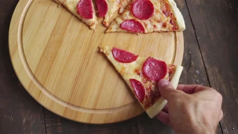 Man take a pepperoni pizza slice from round board Stock Footage 190769954