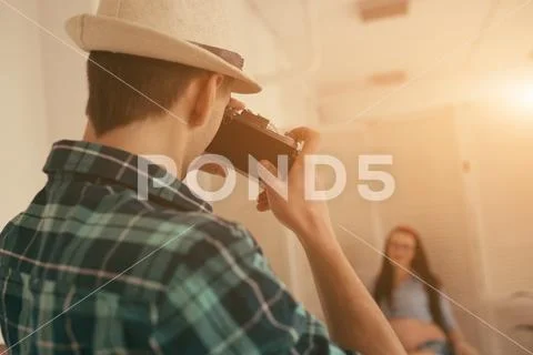 Man take a photo of pregnant woman in loft interior with old soviet camera Stock Photos