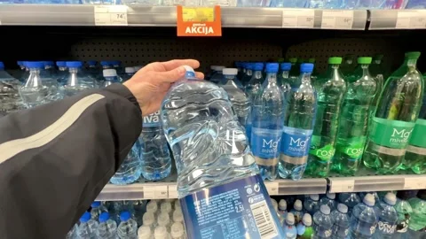 A man takes and examines a bottle of water in a grocery store Stock Footage 237953554