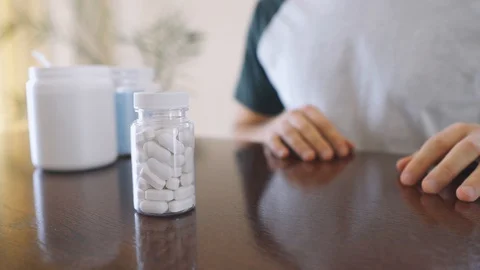 Man takes and shows pills vitamins or drugs tablets in hand from pill bottle Stock Footage 125637053