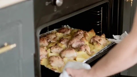 Man takes baking tray with fried chicken and potatoes out of the oven for dinner Stock-Footage 229559413