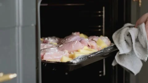 Man takes baking tray with raw chicken and potatoes in the oven for dinner Stock-Footage 229559389
