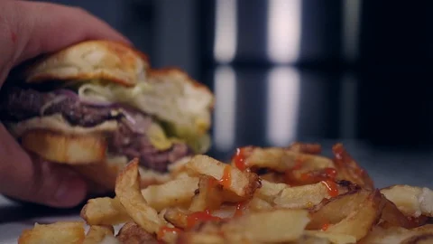 Man takes a bite of a cheeseburger from a fast food restaurant 스톡 동영상 118046222
