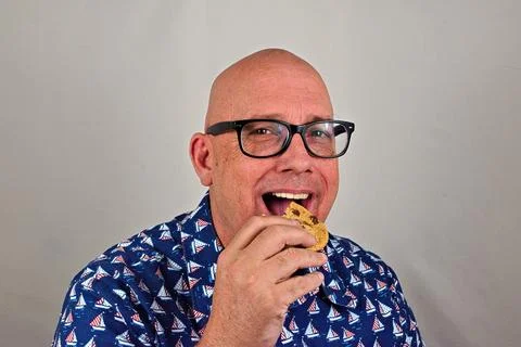 A man takes a bite of a chocolate chip cookie Stock Photos