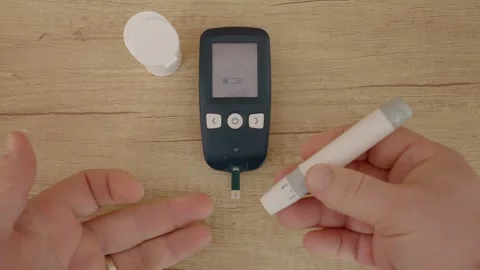 Man takes blood sugar test using glucometer and glucose strip in home setting Stock Footage 346703690