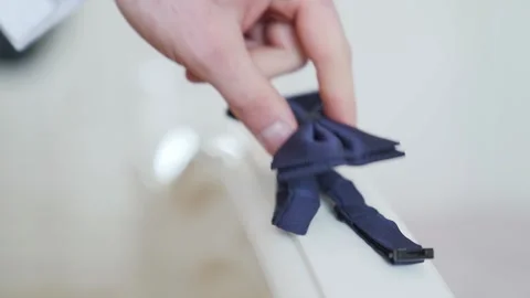 Man takes blue bow tie from a white surface. Slow motion Stock Footage 221017533