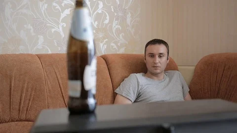 Man takes a bottle of beer, standing on the old TV. Man drinks the beer. Stock Footage 69816072