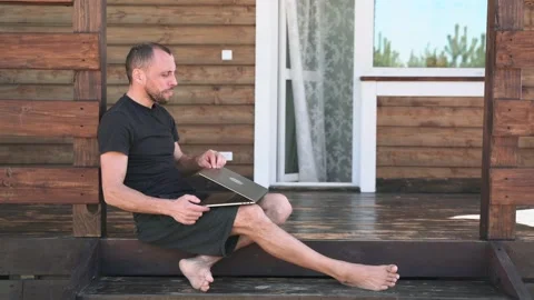 A man takes a break closing his laptop and enjoying nature sitting on the Stock Footage 154100011