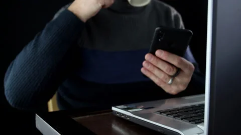 A man takes a break drinking tea and typing on his smartphone Stock Footage 144340577