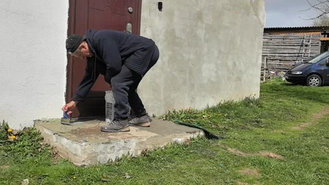 Man takes a break while painting and checking door near a house Stock Footage 340187163
