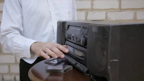 The man takes the cassette and inserts another into old outdated tape recorder 库存影片 69777830